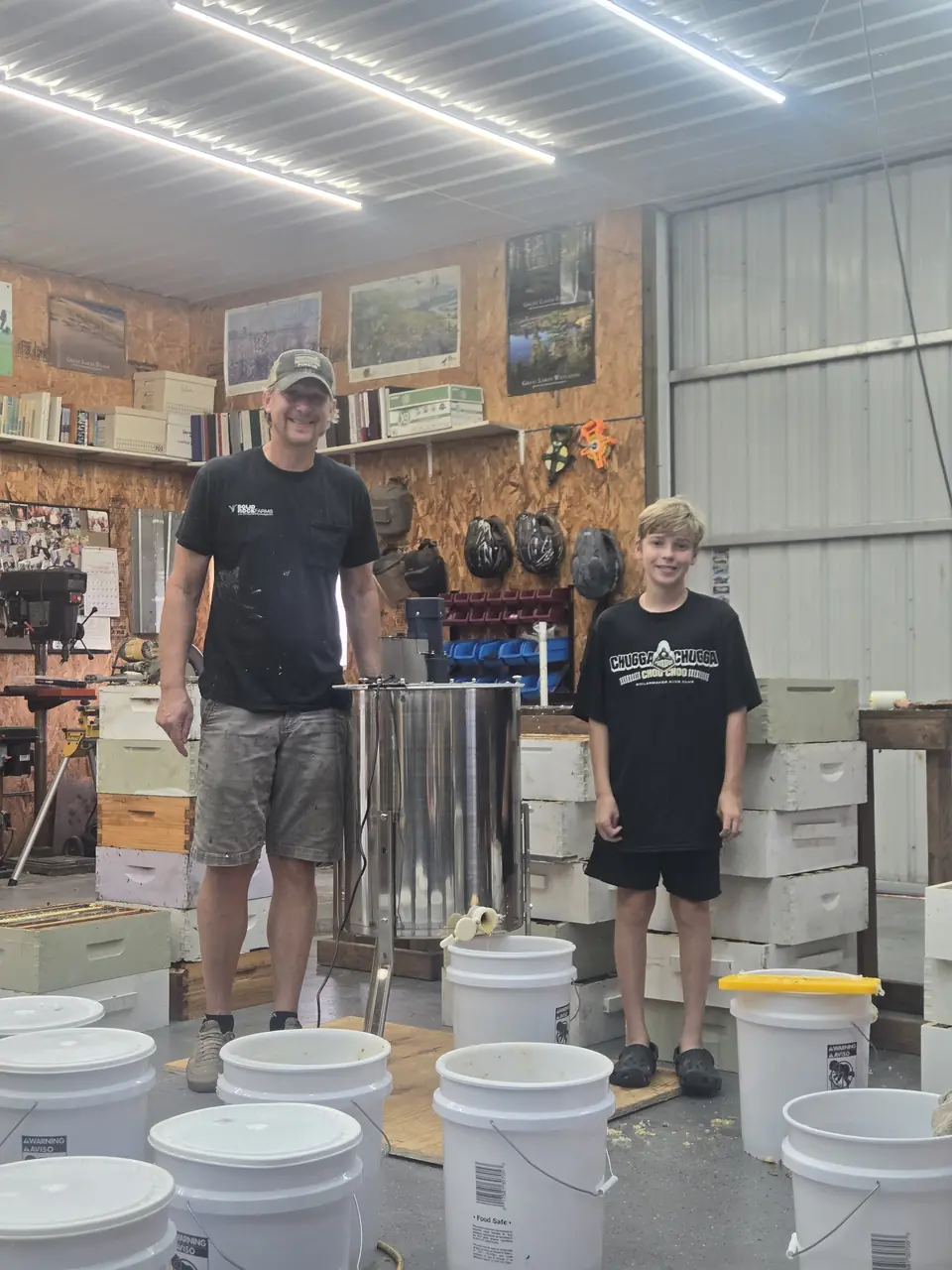 Two family members beside the extractor and buckets of harvested honey