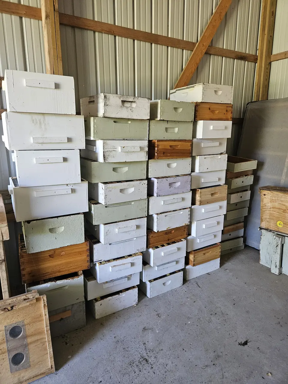 Stacks of wooden hive boxes and honey supers inside the barn